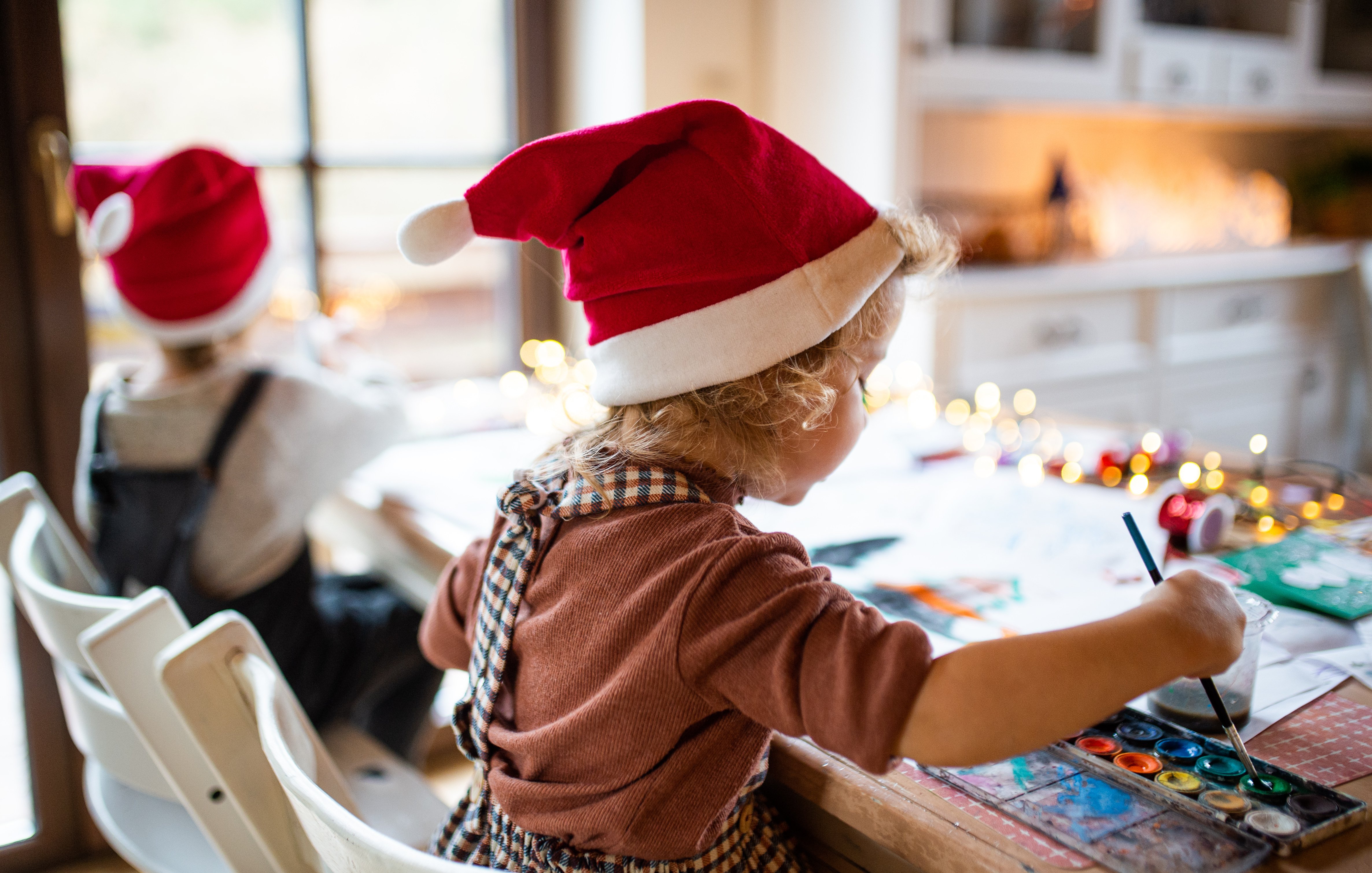 a child in a santa hat painting a christmas bauble