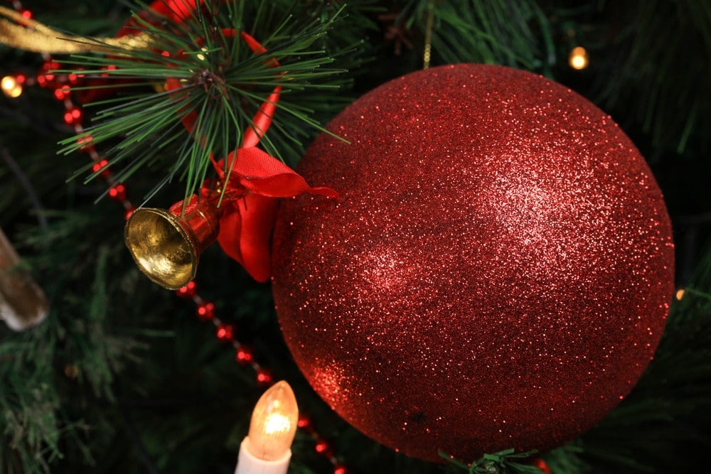 Big red glittery bauble with a small small bell ornament, red beaded garland and a fake candle