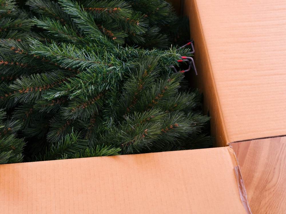Green branches from an artificial christmas tree in a large cardboard box