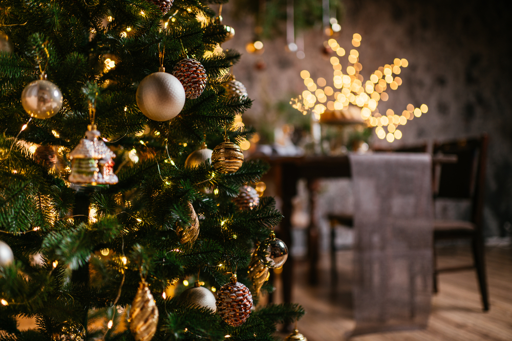 Close up view of a decorated christmas tree with blurred table and chairs in the back