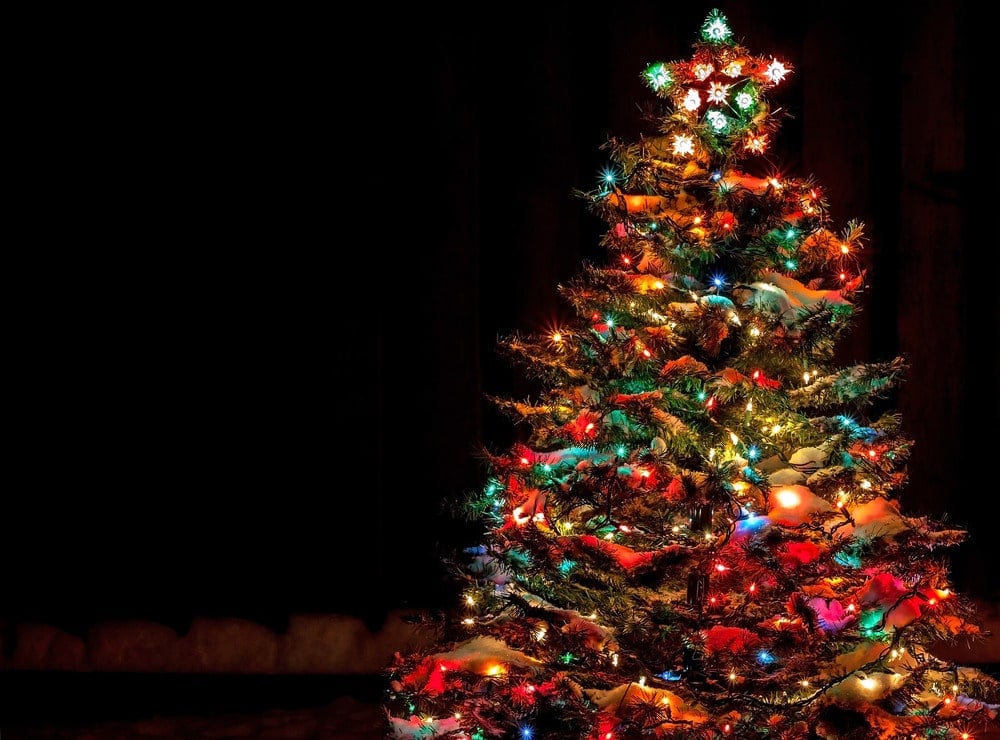 Multi-coloured Christmas tree lights with snow and a star topper