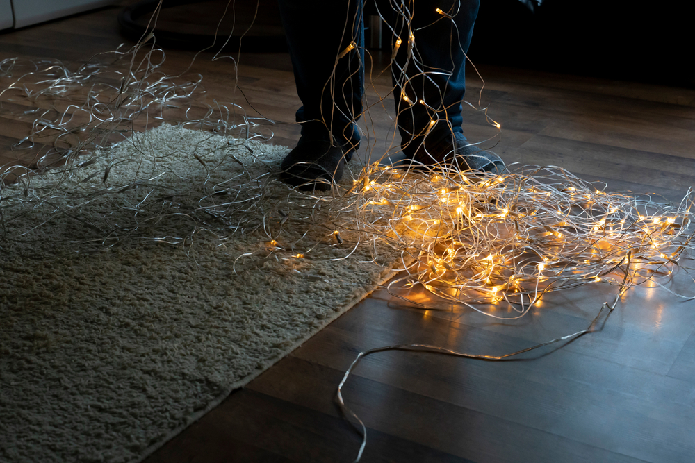 Person unravelling a pile of Christmas lights that are on the floor