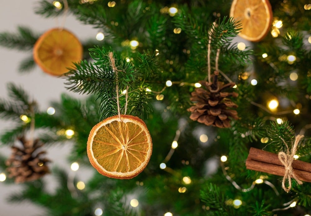 Close up of a christmas tree with orange slices, cinnamon sticks, pinecones and fairy lights