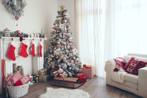 a white snowy artificial christmas tree in a decorated living room